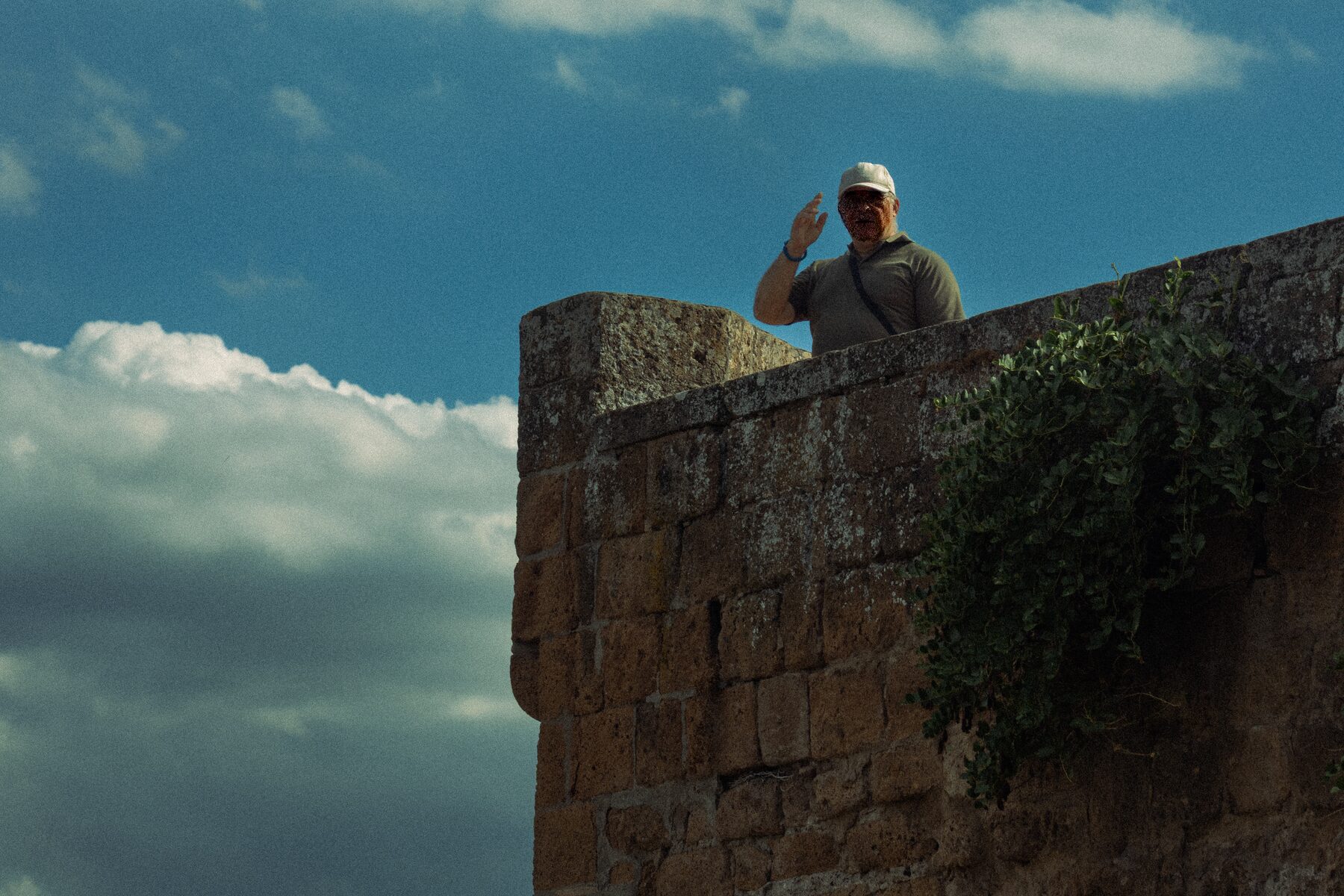 Portrait of a man atop an ivy-covered stone fortress wall