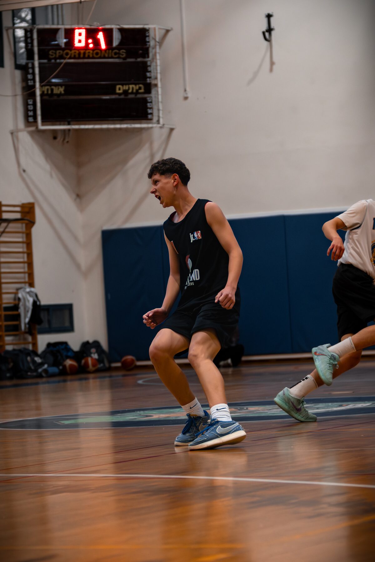 Basketball player celebrating mid-run beside the scoreboard