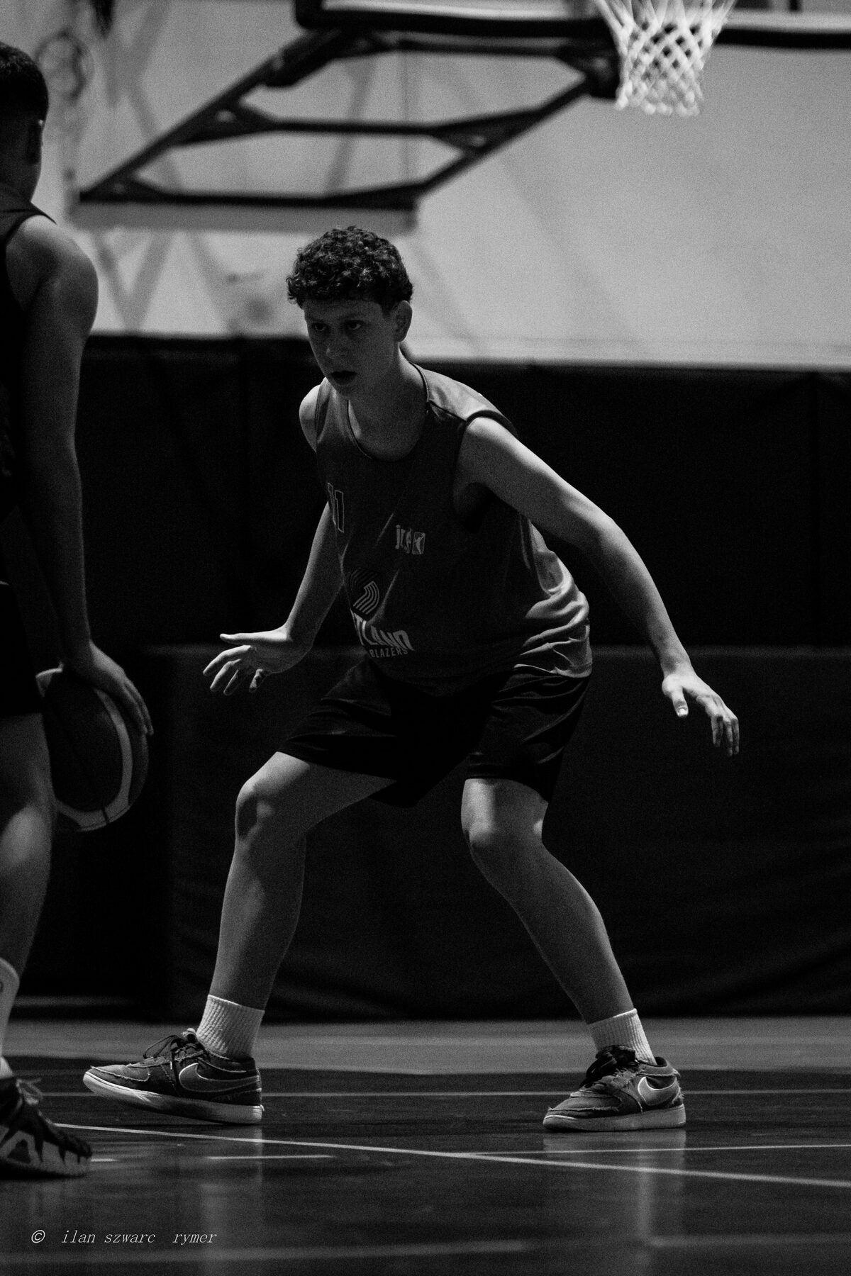 Black and white photo of a young basketball player in a defensive stance