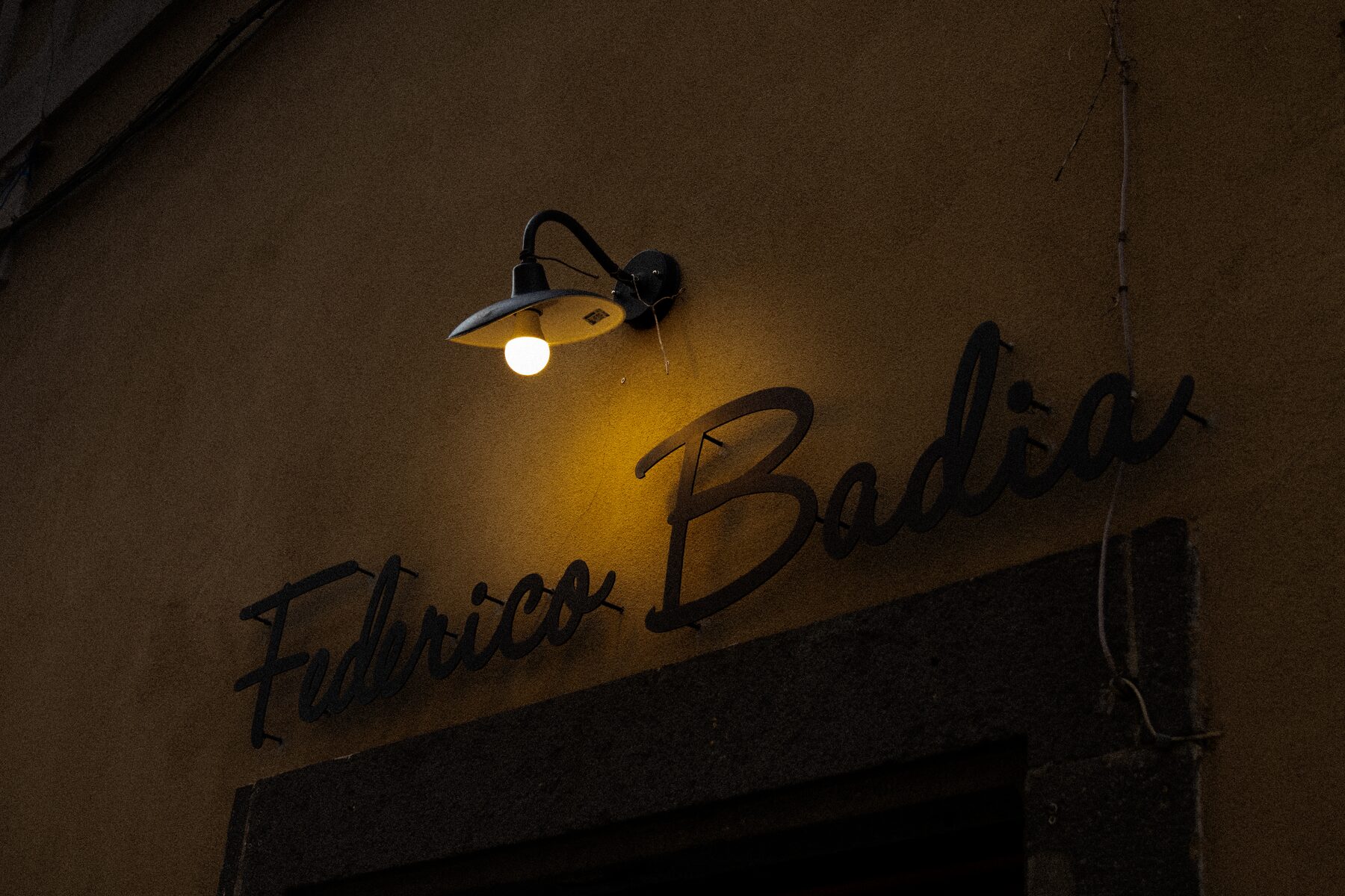 A lit storefront sign reading Federico Badia glowing at dusk